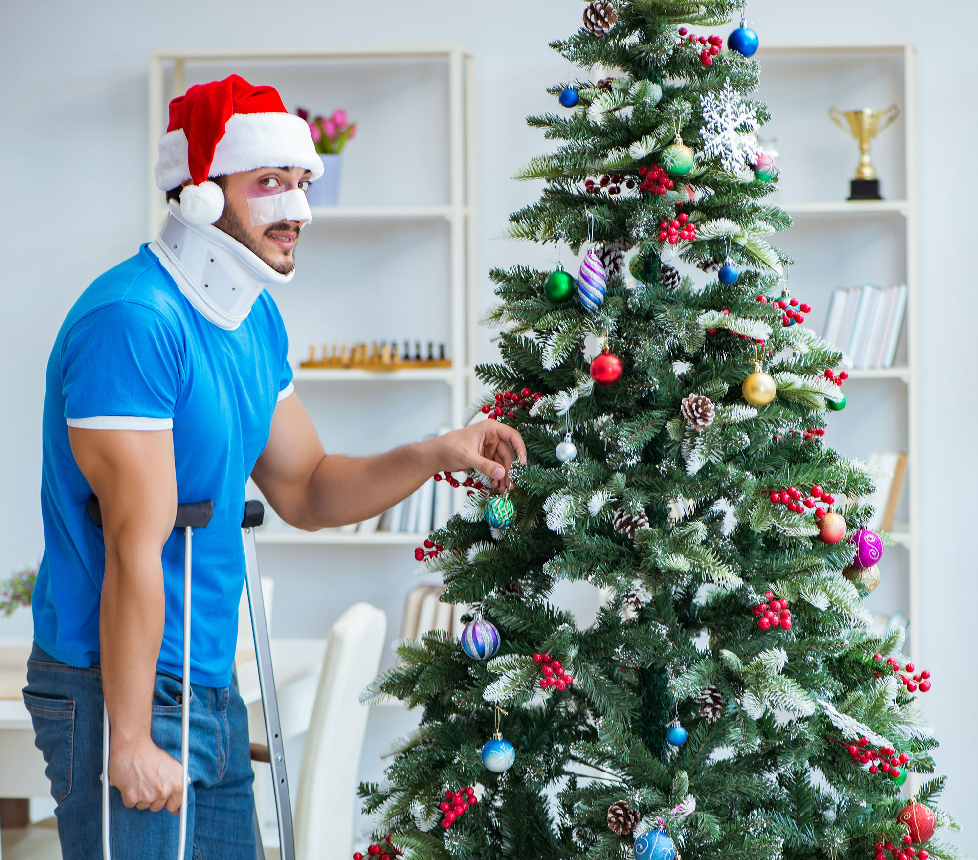 Hombre con muletas decorando un árbol de Navidad con dolor